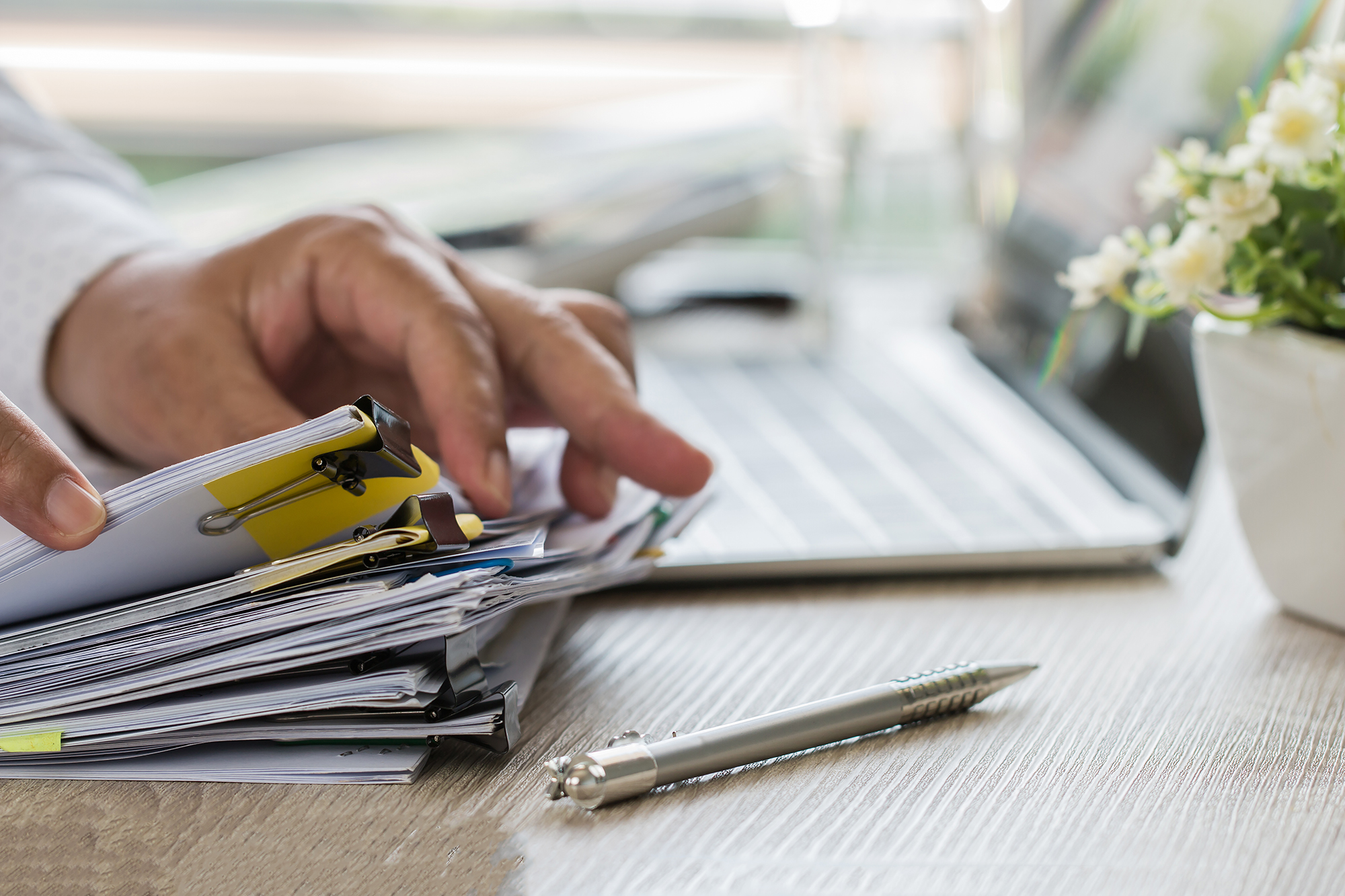 Businessman hands holding pen for working in Stacks of paper fil